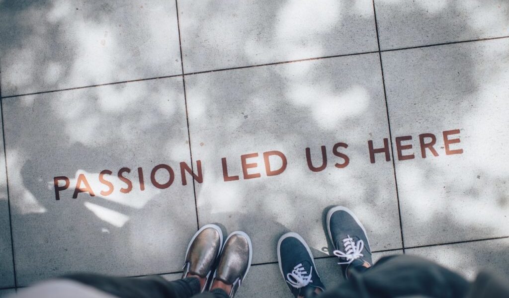 zdjęcie nóg na chodniku, na którym jest napisane passion led us here);