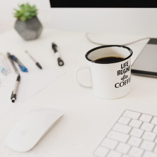 zdjęcie białego biurka a na nim białego kubka, białej myszki i białej klawiatury);